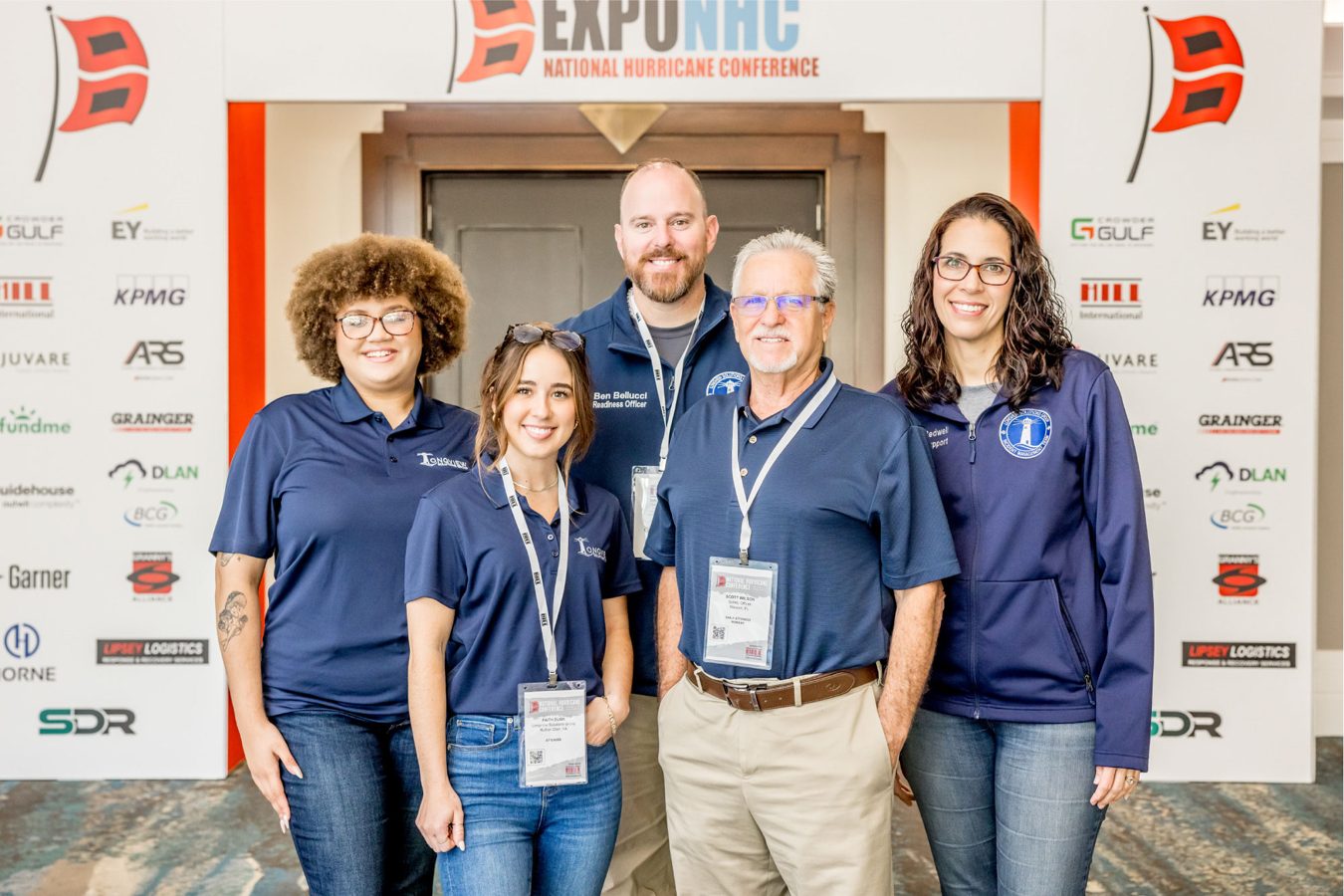 Conference team posing in front of event branding